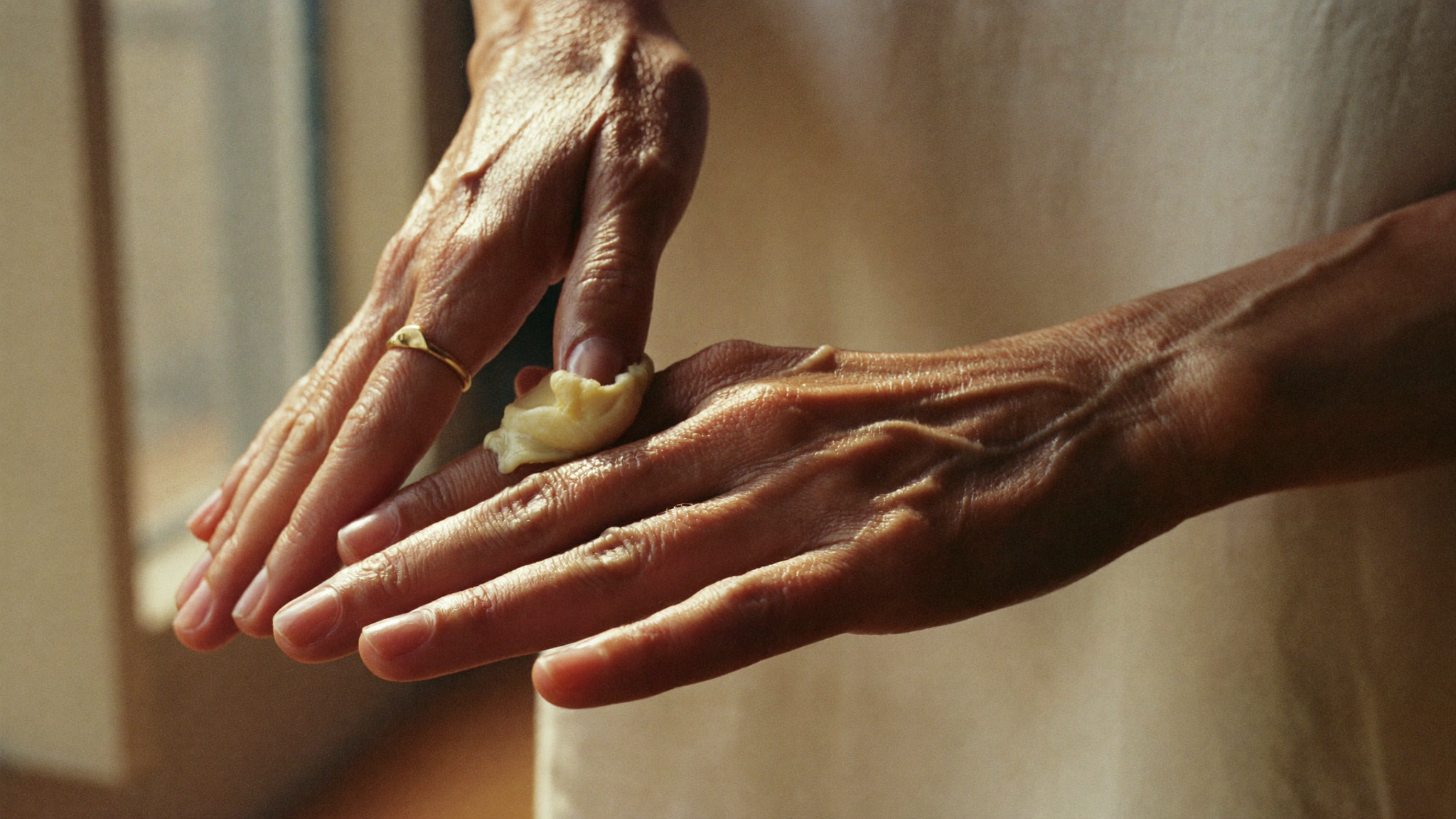 Manos calentando una pomada rica en vitamina A entre las yemas de los dedos con luz suave de la mañana