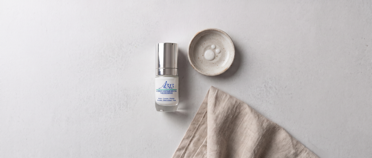 A313 Eye Serum bottle in an overhead flatlay beside a small dish and folded linen cloth