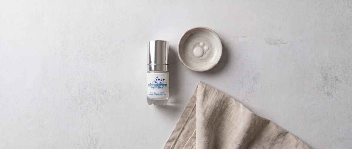 A313 Eye Serum von oben fotografiert, daneben ein kleines Keramikschälchen und ein gefaltetes Leinentuch im weichen Tageslicht
